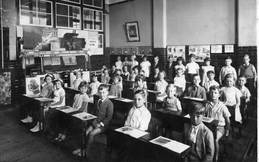 black and white photo of elementary school students sitting in a classroom