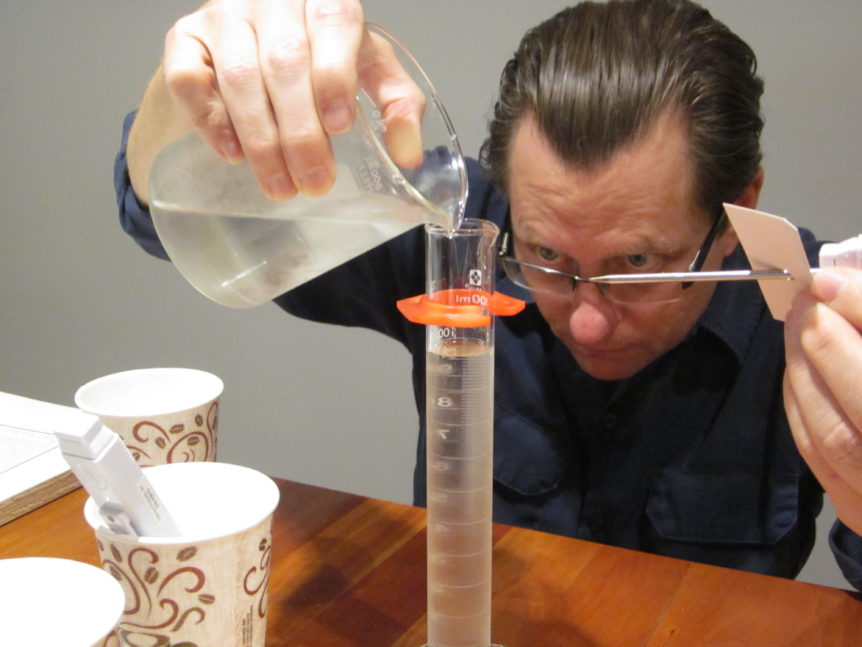 John Mays pouring a clear liquid into a graduated cylinder